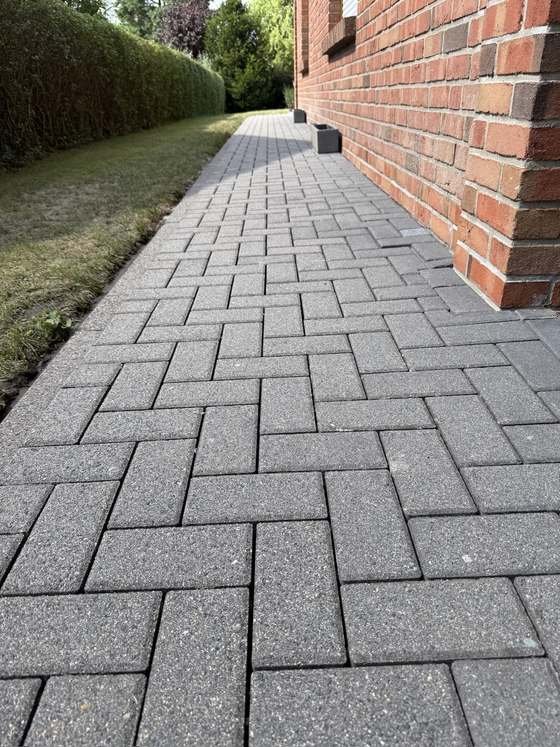 Gereinigter Gehweg entlang der Klinkerwand, dunkles Pflaster mit klarem Fugenbild