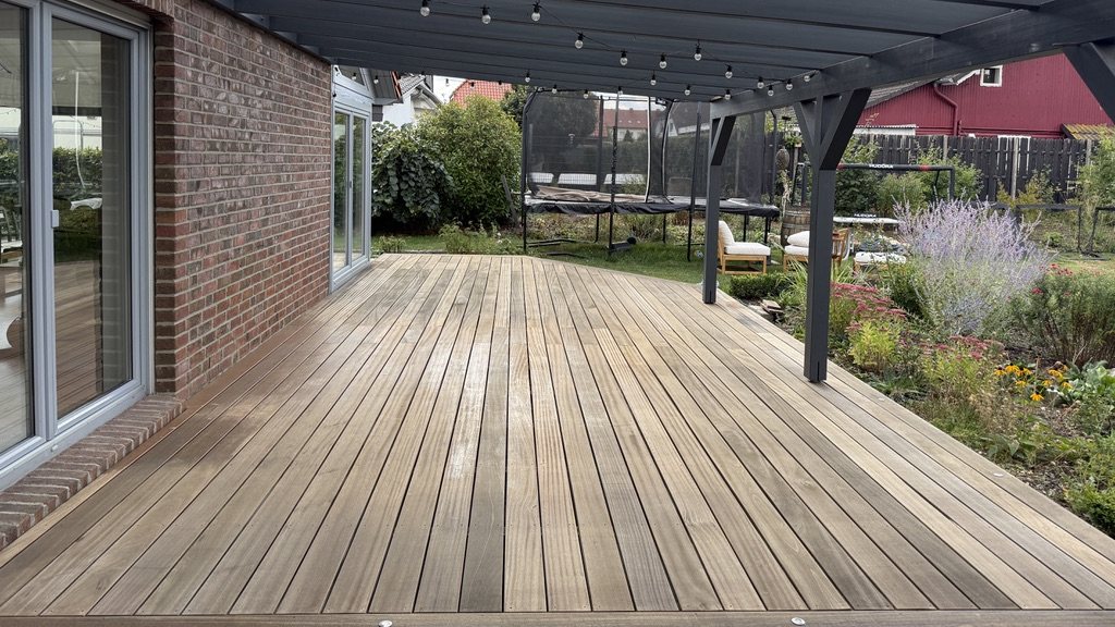 Gereinigte Holzterrasse unter einer Pergola in Wolfsburg, die Dielen wieder in ihrer Holzfarbe