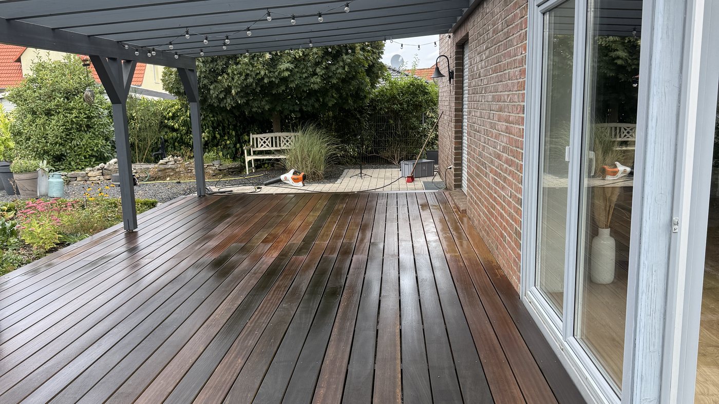 Die frisch gereinigte Holzterrasse, noch nass und dadurch dunkel und fleckig