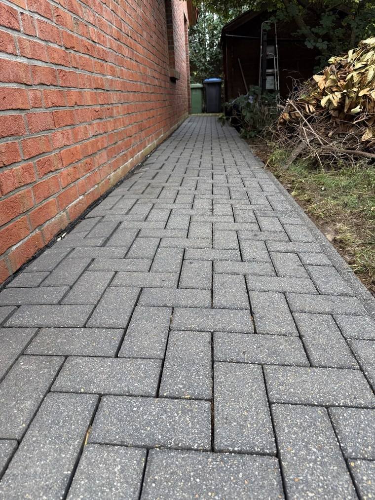 Derselbe Weg nach der Reinigung, durchgehend sauberes Pflaster bis ans Ende des Hauses