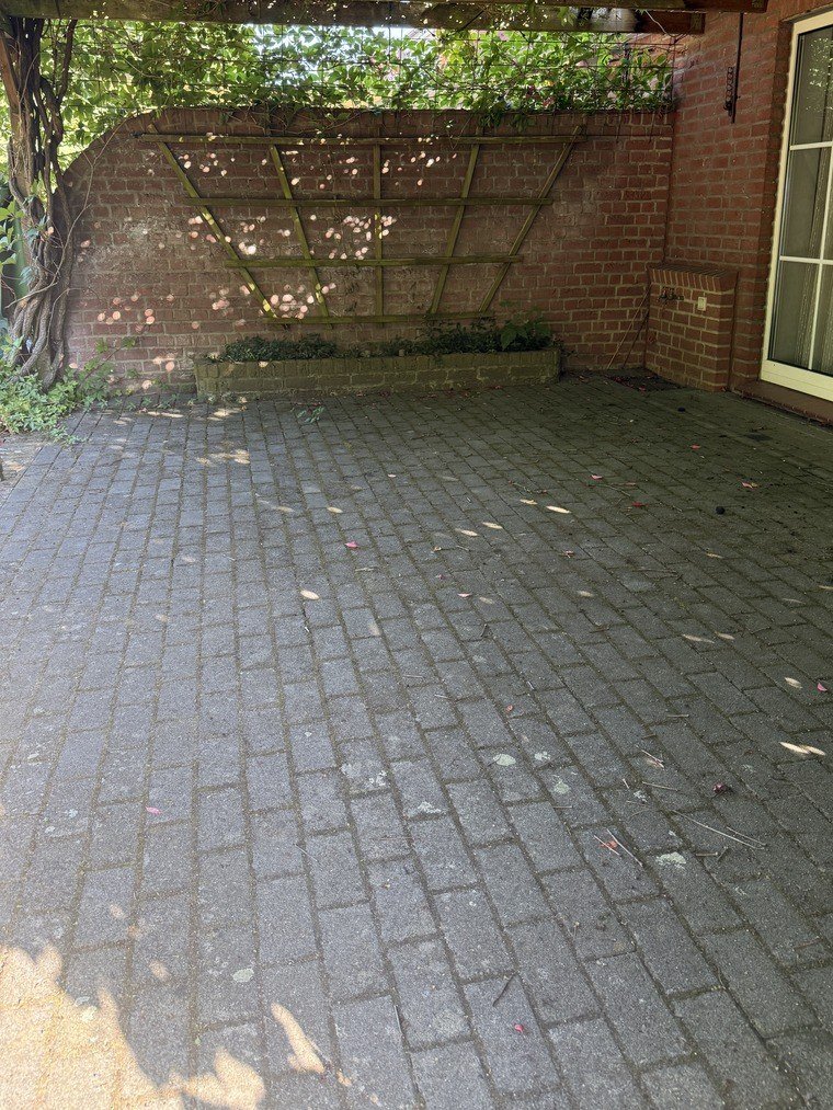 Überdachte Terrasse an der Klinkerwand vor der Reinigung, das Pflaster flächig vergraut